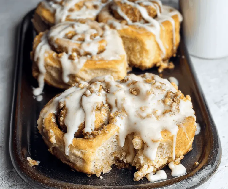 Delicious apple pie stuffed cinnamon rolls topped with caramel and powdered sugar, perfect for a comforting breakfast or dessert.