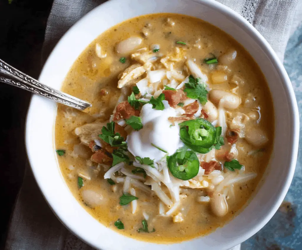 Creamy White Bean Enchilada Soup in a bowl garnished with cilantro and cheese, served with tortilla chips on the side