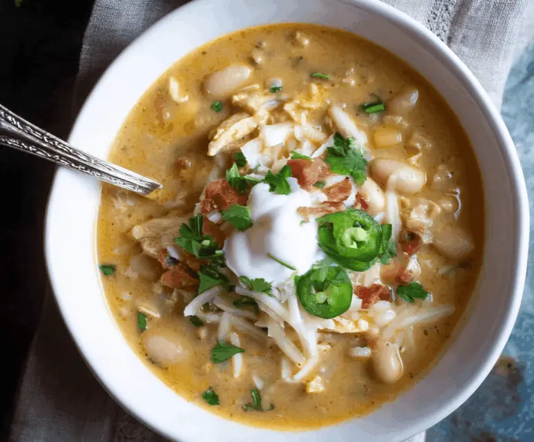 Creamy White Bean Enchilada Soup in a bowl garnished with cilantro and cheese, served with tortilla chips on the side