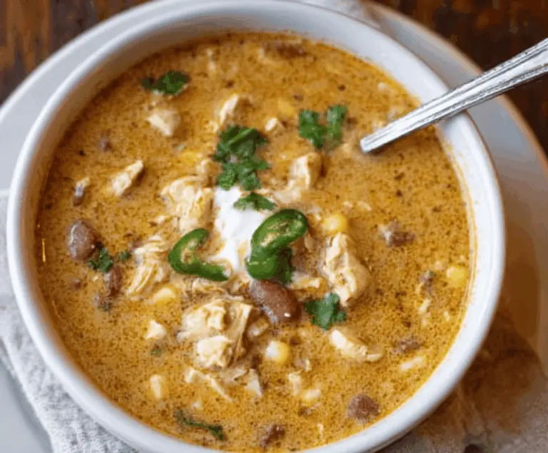 Creamy Cajun White Chicken Chili topped with fresh herbs and shredded cheese in a rustic bowl