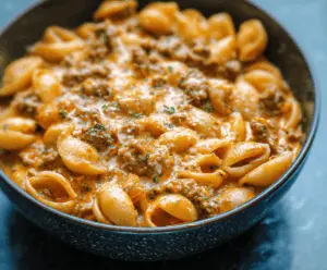 Creamy beef and pasta shells in a savory sauce served in a white bowl, garnished with fresh herbs for a delicious comfort meal.