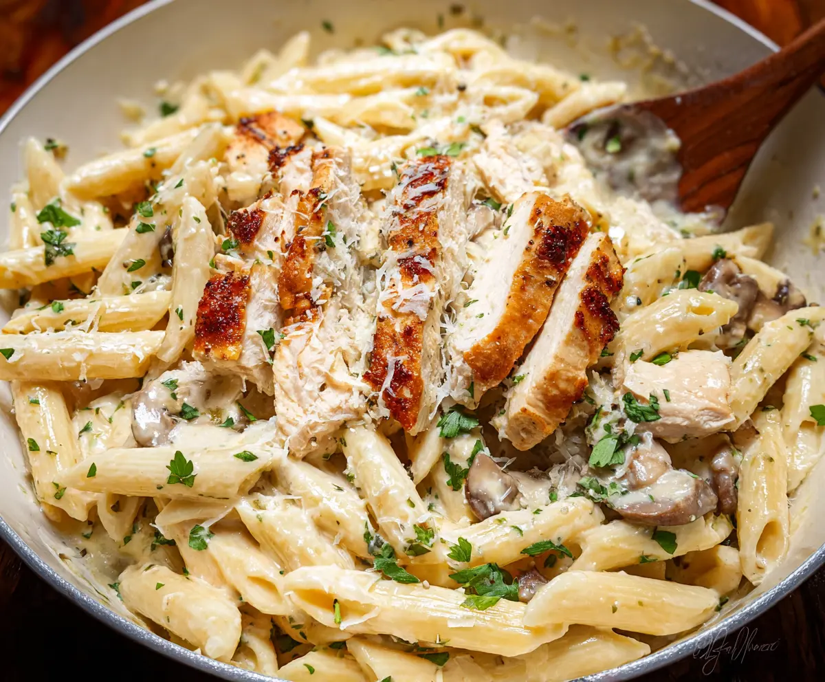 Creamy Chicken Alfredo pasta dish garnished with parsley on a white plate.