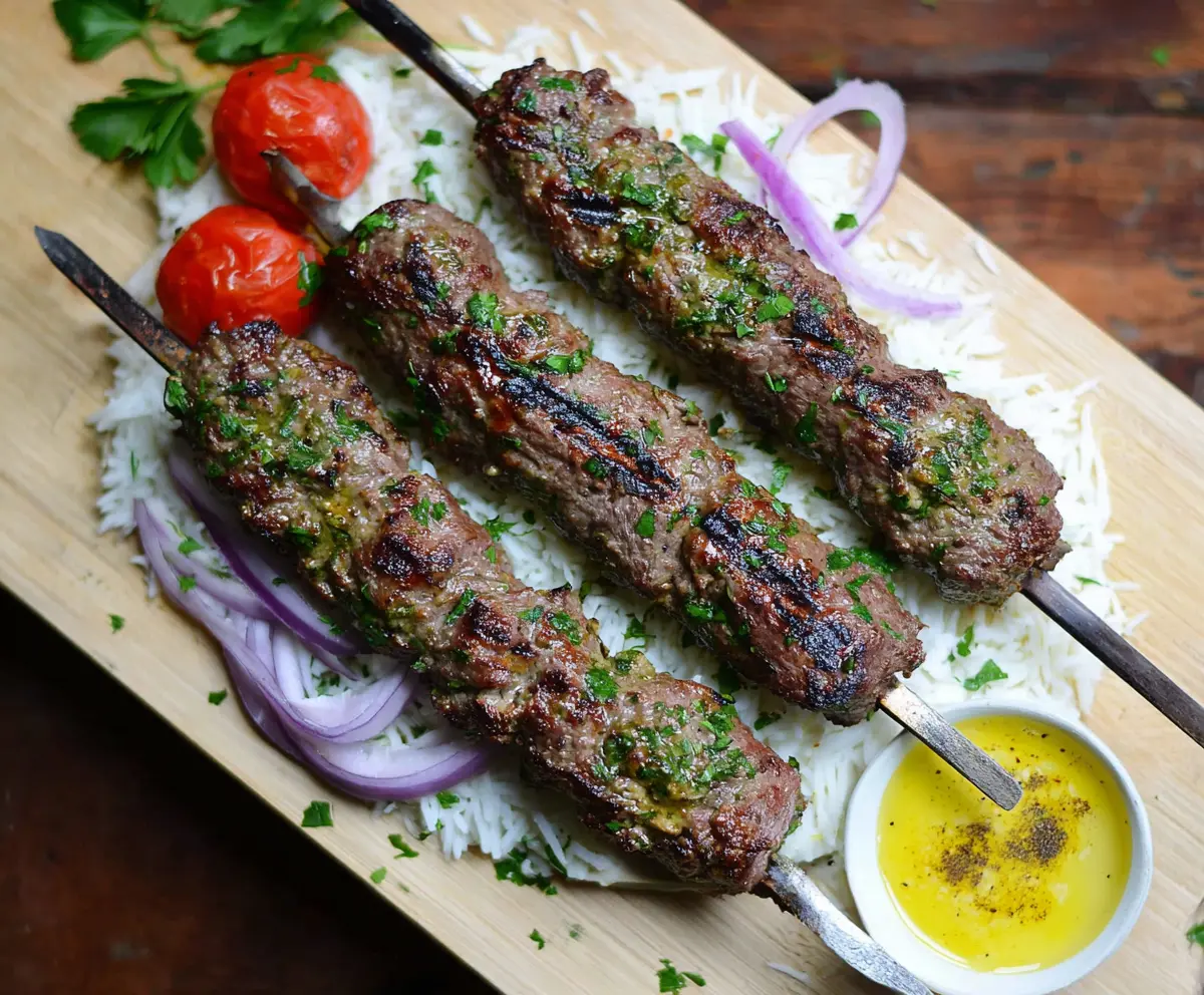 Juicy Beef Kafta Kebabs grilled to perfection on a skewer, served with fresh herbs and vegetables.