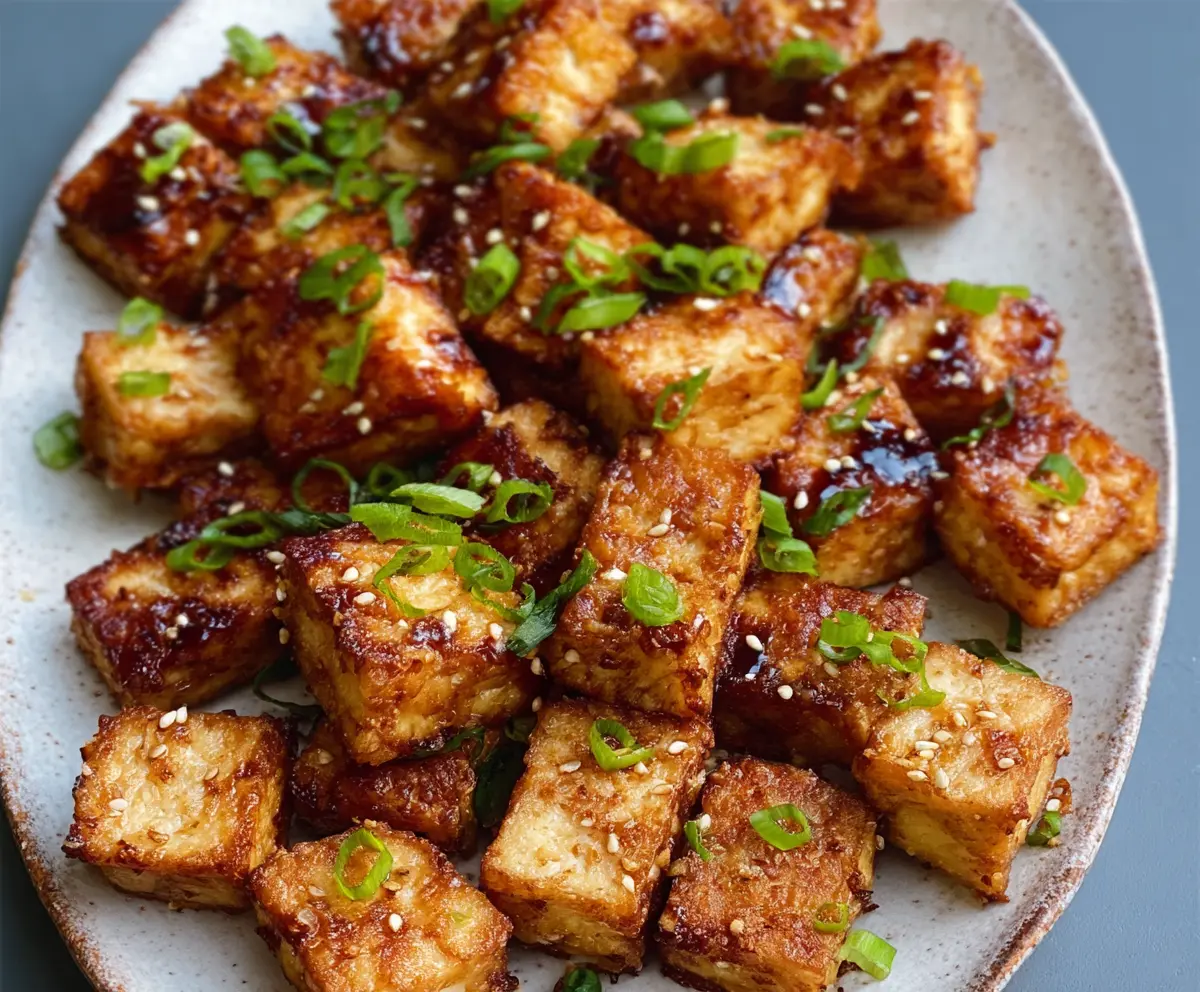 Crispy Air Fryer Tofu served on a white plate with fresh vegetables, perfect for a healthy vegetarian meal.