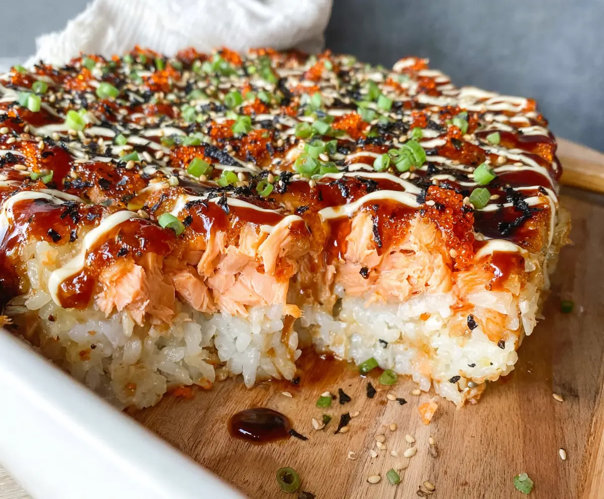 Delicious Spicy Salmon Sushi Bake topped with fresh herbs and sesame seeds.