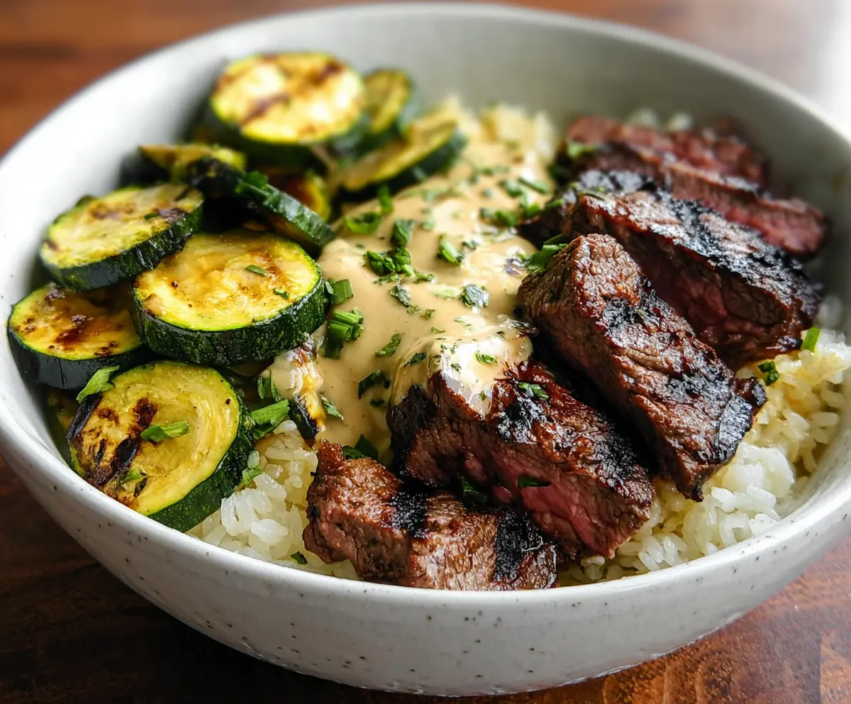 Delicious grilled steak bowl topped with fresh zucchini slices, perfect for a healthy meal.